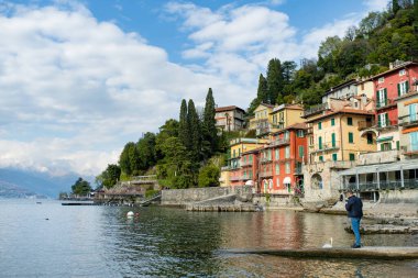 VARENNA, İtalya - Nisan 2022: Turistler ve yerliler, Como Gölü kıyısındaki bir kasaba olan Varenna 'da güneşli bir bahar günü geçiriyorlar. Tipik İtalyan atmosferiyle büyüleyici bir yer. Varenna, Lombardy, İtalya.