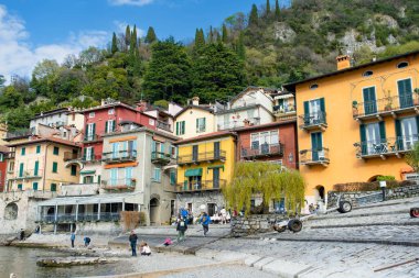 VARENNA, İtalya - Nisan 2022: Turistler ve yerliler, Como Gölü kıyısındaki bir kasaba olan Varenna 'da güneşli bir bahar günü geçiriyorlar. Tipik İtalyan atmosferiyle büyüleyici bir yer. Varenna, Lombardy, İtalya.