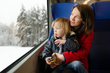 Genç anne ve küçük oğlu trenle seyahat ediyorlar. Anne ve küçük çocuk aile tatilinde ekspres trende pencerenin kenarında oturuyorlar. Tren vagonunda bir aile. Küçük çocuklarla tatile gidiyorum..