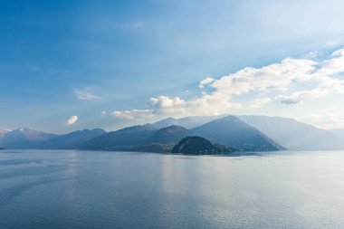 Güneşli yaz gününde ünlü Como Gölü 'nün güzel hava manzarası. Gölün sakin sularına yansıyan bulutlar ve arka planda Alp dağları. Lombardy, İtalya.