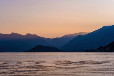 Mor gün batımında ünlü Como Gölü 'nün güzel hava manzarası. Bulutlar gölün sakin sularına yansıyor ve arka planda Alp dağı sıraları var. Lombardy, İtalya.
