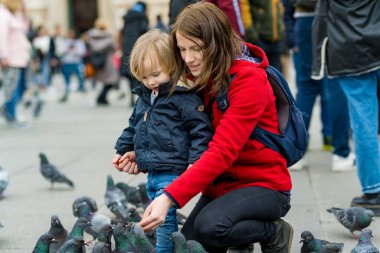 Genç anne ve küçük oğlu İtalya 'nın başkenti Milan' daki Katedral Meydanı veya Piazza del Duomo 'da güvercinleri besliyor..