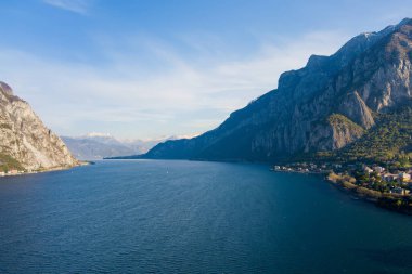 Güneşli yaz gününde ünlü Como Gölü 'nün güzel hava manzarası. Gölün sakin sularına yansıyan bulutlar ve arka planda Alp dağları. Lombardy, İtalya.