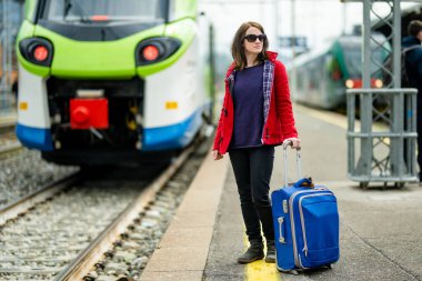 Tren istasyonunda genç bir kadın. Platformda tren bekleyen bir kız. Seyahate hazır valizli bir bayan turist. Tek başıma tatile çıkıyorum..