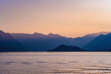 Mor gün batımında ünlü Como Gölü 'nün güzel hava manzarası. Bulutlar gölün sakin sularına yansıyor ve arka planda Alp dağı sıraları var. Lombardy, İtalya.