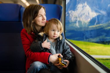 Genç anne ve küçük oğlu trenle seyahat ediyorlar. Anne ve küçük çocuk aile tatilinde ekspres trende pencerenin kenarında oturuyorlar. Tren vagonunda bir aile. Küçük çocuklarla tatile gidiyorum..