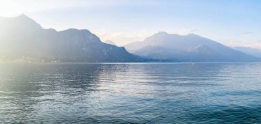 Güneşli yaz gününde ünlü Como Gölü 'nün güzel hava manzarası. Gölün sakin sularına yansıyan bulutlar ve arka planda Alp dağları. Lombardy, İtalya.