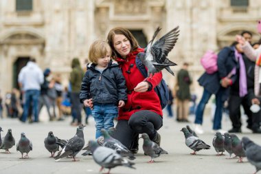 Genç anne ve küçük oğlu İtalya 'nın başkenti Milan' daki Katedral Meydanı veya Piazza del Duomo 'da güvercinleri besliyor..