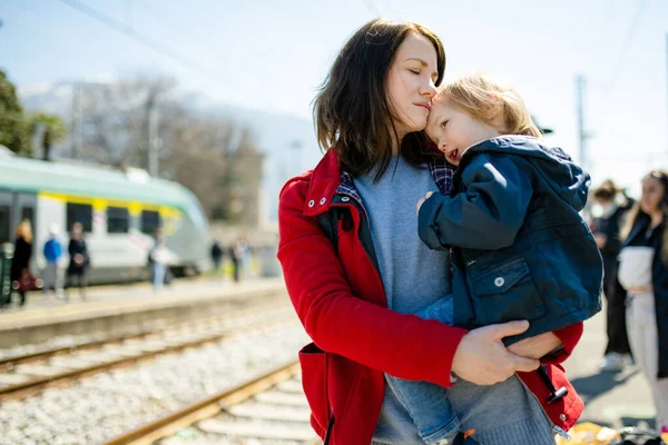 年轻的母亲和她蹒跚学步的儿子在火车站 妈妈和小孩在月台上等火车 家人都准备好旅行了和小孩一起去度假 — 图库照片