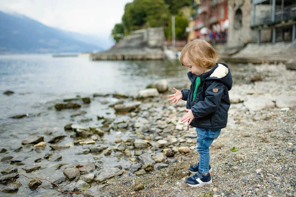 かわいい幼児の男の子は コモ湖の海岸で最も絵のように美しい町の1つであるバレンナ港の小石で遊んでいます バレンナ ロンバルディア州 イタリア — ストック写真