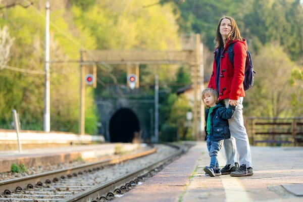 若い母親と鉄道駅で彼女の幼児の息子 お母さんと子供がホームで電車を待っている 家族旅行の準備ができています 小さな子供たちと休暇に行く — ストック写真