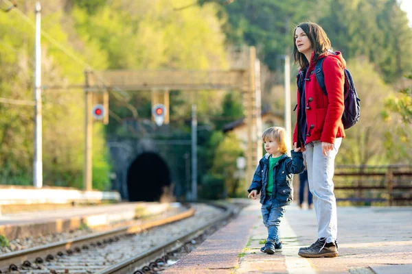 年轻的母亲和她蹒跚学步的儿子在火车站 妈妈和小孩在月台上等火车 家人都准备好旅行了和小孩一起去度假 — 图库照片
