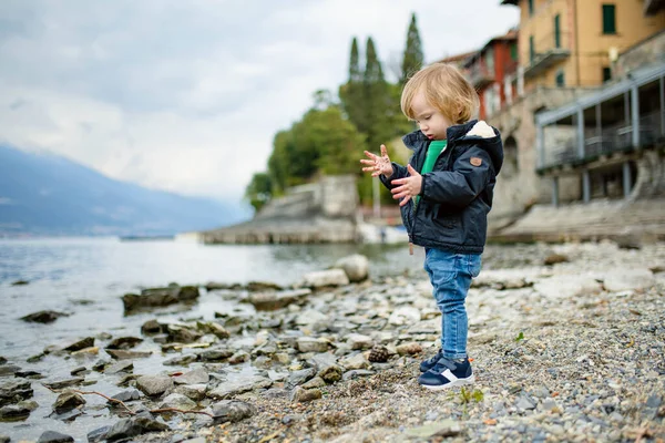 かわいい幼児の男の子は コモ湖の海岸で最も絵のように美しい町の1つであるバレンナ港の小石で遊んでいます バレンナ ロンバルディア州 イタリア — ストック写真