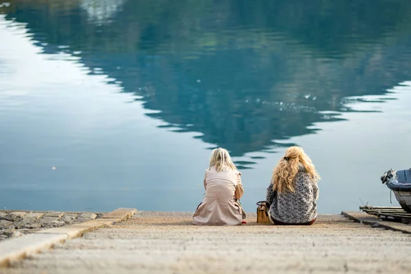 早春的一天 两名年轻妇女坐在Lecco镇的堤岸上 朋友们欣赏位于科莫湖畔的莱科海滨风景如画 意大利的度假目的地 — 图库照片