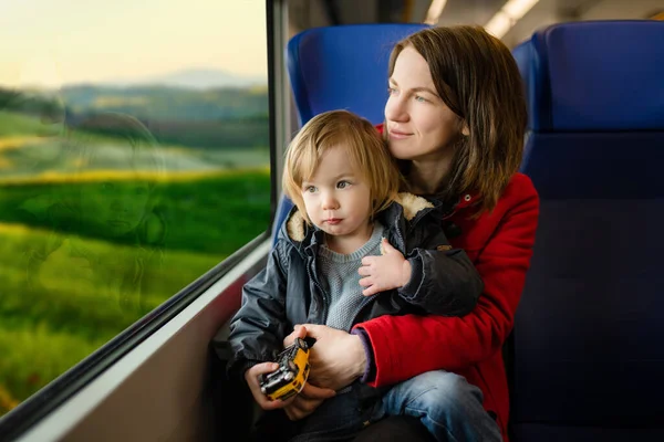 電車で旅行する若い母親と彼女の幼児の息子 家族の休暇に急行列車で窓のそばに座っているお母さんと小さな子供 電車の中で家族 小さな子供たちと休暇に行く — ストック写真
