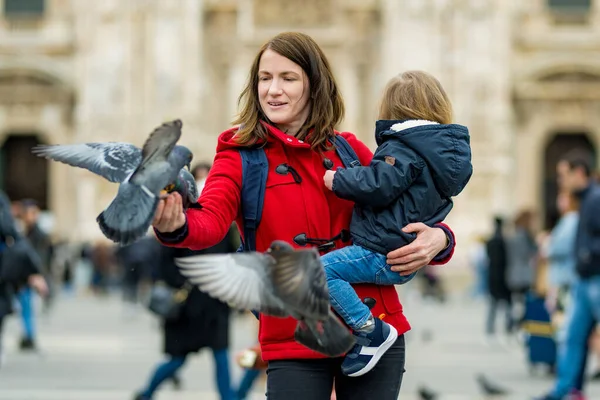 イタリアのロンバルディア州ミラノの中心部にある大聖堂広場やドゥオーモ広場で鳩を養う若い母親と彼女の幼児の息子 — ストック写真