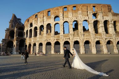 ROME, ITALY - MAYIS 2011: Colosseum 'un önündeki düğün çifti, bir zamanlar gladyatör oyunları için kullanılan anıtsal Roma amfi tiyatrosu, güneşli bir yaz gününde Roma, Lazio, İtalya' da.