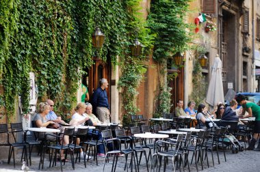 Roma, İtalya 2011: bir açık hava restoranında oturan turistler ve yerel halk. Roma 'nın merkezinde yaz boyunca insanlarla dolu kalabalık bir yaya caddesi. Roma, Lazio, İtalya.