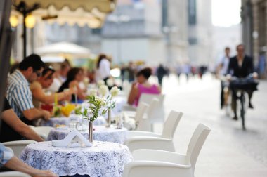 MILAN, ITALY - Mayıs 2011: İtalya 'nın kuzey Lombardiya bölgesinde yer alan bir metropol olan Milano' nun merkezindeki işlek caddenin dışındaki açık kafede oturan turistler ve yerel halk. Milan, Lombardiya, İtalya.