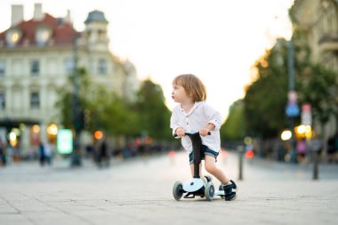 Yazın dışarıda bebek scooter 'ı süren komik çocuk. Küçük bisiklette çocuk dengesi. Küçük çocuklar için yaz etkinlikleri.