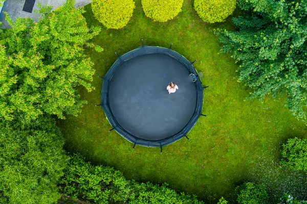 空中俯瞰着一个少女在后院跳上蹦床的情景 后院里的孩子们很好玩夏季户外休闲活动 — 图库照片
