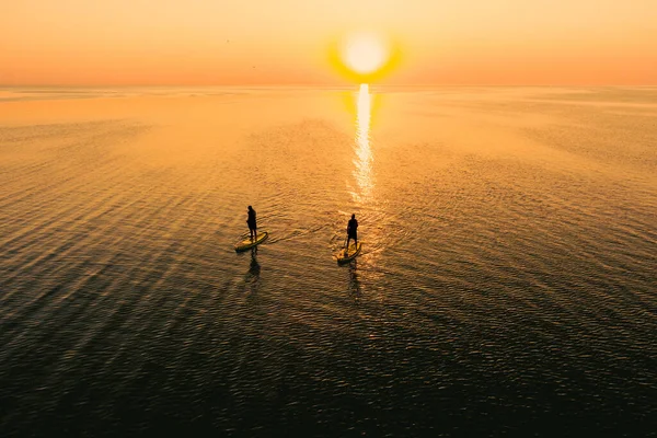 Gün Batımında Sakin Denizde Ayakta Duran Iki Kişinin Hava Görüntüsü — Stok fotoğraf