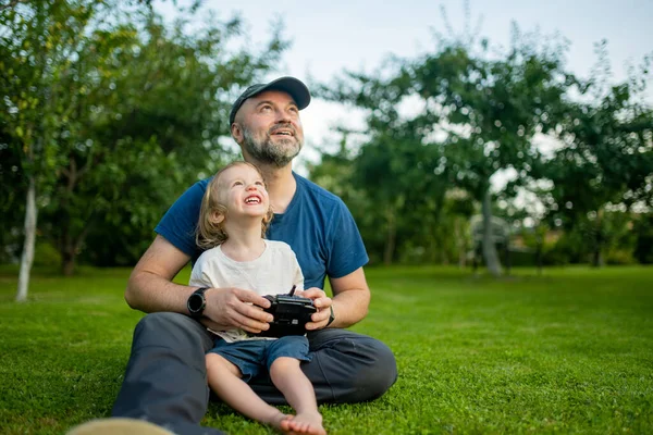 父と息子は無人機を見てナビゲートします かわいい幼児の男の子は 父親が遠隔操作でドローンを操作するのを助けています ファミリーレジャー — ストック写真