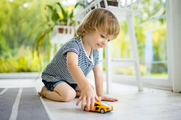 可爱的小孩在玩黄色的玩具车 小孩子玩玩具玩得很开心 孩子们在舒适的客厅里呆着 室内家庭休闲 — 图库照片