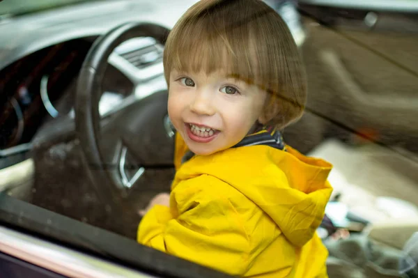 可爱的蹒跚学步的男孩在驾驶座上玩耍 可爱的小儿子坐在父亲的车里 在车上玩乐的小孩 — 图库照片