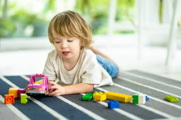かわいい幼児の男の子が家の床にブロックの建設おもちゃをセットして遊んでいます 昼間のケア創造的な活動 おもちゃで遊んでいる子供たち 教育学習ゲーム ファミリーレジャー屋内 — ストック写真