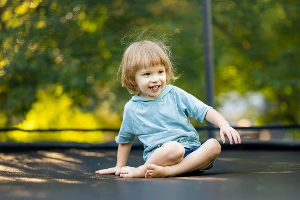 在温暖而阳光灿烂的夏日 可爱的幼儿在后院跳上蹦床 儿童体育和运动 夏季户外休闲活动 — 图库照片