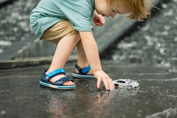 可爱的小孩在户外玩黄色的玩具车 孩子们在城市的喷泉里玩水幼儿暑期活动 — 图库照片