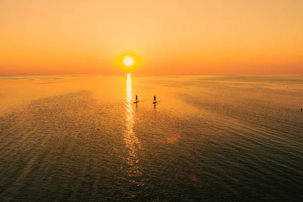 Gün Batımında Sakin Denizde Ayakta Duran Iki Kişinin Hava Görüntüsü — Stok fotoğraf