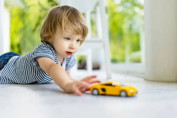 黄色のおもちゃの車で遊んでかわいい幼児の少年 おもちゃで楽しんでいる小さな子供 子供は家の居心地の良いリビングルームで時間を過ごしています 屋内ファミリーレジャー — ストック写真