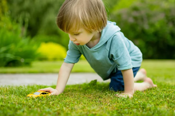 可爱的小孩在户外玩黄色的玩具车 小孩在探索自然小孩子玩玩具玩得很开心 幼儿暑期活动 — 图库照片