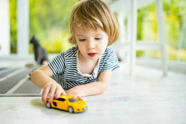可爱的小孩在玩黄色的玩具车 小孩子玩玩具玩得很开心 孩子们在舒适的客厅里呆着 室内家庭休闲 — 图库照片