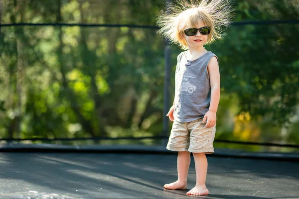 可爱的小孩戴着太阳镜 乱蓬蓬的头发跳到后院的蹦床上 儿童体育和运动 夏季户外休闲活动 — 图库照片
