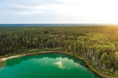 Gela Gölü 'nün güzel yeşil sularının havadan görünüşü. Çam ormanlarıyla çevrili zümrüt göl manzaralı kuş bakışı. Litvanya 'nın Vilnius kenti yakınlarındaki Gela gölünde yansıyan bulutlar.