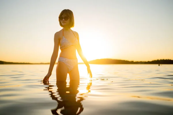 暖かくて日当たりの良い夏の夜に湖で楽しむ美しい十代の少女のシルエット 夕日のきれいな若い女の子 家族の夏の活動 — ストック写真
