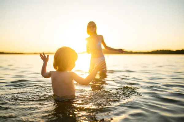 かわいい幼児の男の子と彼の十代の妹は暑い夏の日に湖で遊んでいます 夏の休暇中に屋外で楽しい時間を過ごしている愛らしい子供 子供のための水活動 — ストック写真