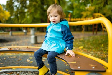 Tatlı çocuk, sıcak bir sonbahar gününde dışarıda oyun alanında eğleniyor. Sonbaharda küçük çocuklar için aktif eğlence.