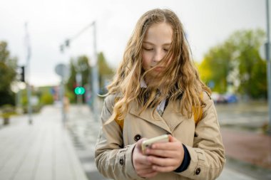 Akıllı telefon kullanan güzel bir genç kız. Sonbahar günü şehir parkında güzel bir genç kız. Gençlerin yeni teknolojiye bağımlılığı.