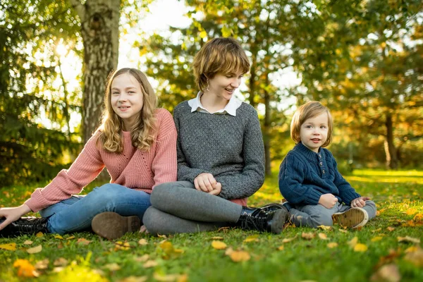 Two big sisters and their toddler brother having fun outdoors. Two young girls with a toddler boy on autumn day. Children with large age gap. Big age difference between siblings. Big family.