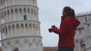 Genç bayan turist ünlü Eğik Pisa Kulesi 'nin fotoğraflarını çekiyor. İtalya 'da tatil, sezon dışı seyahat..