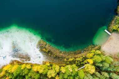 Gela Gölü 'nün güzel yeşil sularının havadan görünüşü. Çam ormanlarıyla çevrili zümrüt göl manzaralı kuş bakışı. Litvanya 'nın Vilnius kenti yakınlarındaki Gela gölünde yansıyan bulutlar.