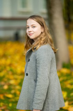 Sevimli genç kız güzel bir sonbahar gününde eğleniyor. Autumn Park 'taki mutlu genç portresi. Çocuklar için sonbahar etkinlikleri.