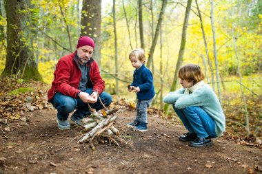 Baba ve çocuklar şenlik ateşinde çubuklarda marşmelov kızartıyorlar. Çocuklar kamp ateşinde eğleniyor. Sonbahar ormanlarında çocuklarla kamp yapmak. Sonbaharda çocuklarla aile eğlencesi..