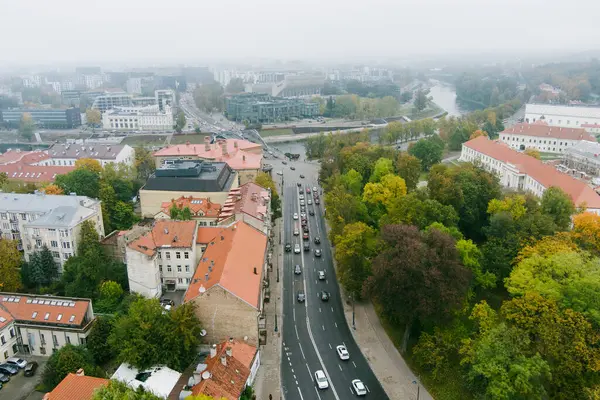 Beautiful foggy Vilnius city scene in autumn with orange and yellow foliage. Aerial early morning view. Fall city scenery in Vilnius, Lithuania.