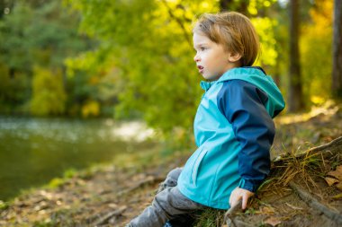 Tatlı çocuk güneşli sonbahar gününde Gela Gölü 'nün yanında eğleniyor. Litvanya 'nın Vilnius şehrinde sonbahar günü doğayı keşfeden çocuk. Çocuklar için eğlenceli sonbahar aktiviteleri.