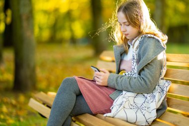 Sevimli genç kız güzel bir sonbahar gününde eğleniyor. Autumn Park 'taki mutlu genç portresi. Çocuklar için sonbahar etkinlikleri.